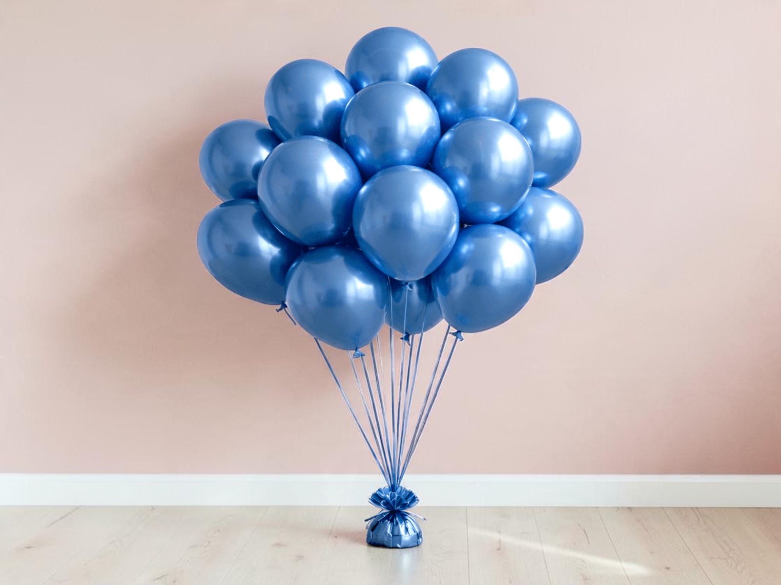 A bunch of blue balloons on a weight in front of a blush pink wall, a simple gender reveal backdrop for a small room