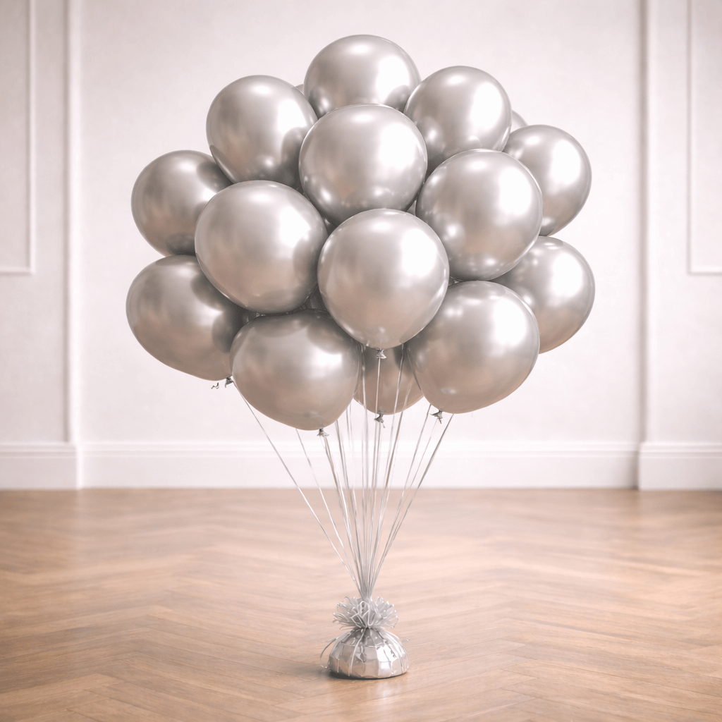 A bunch of silver chrome balloons on a weight in a bright room